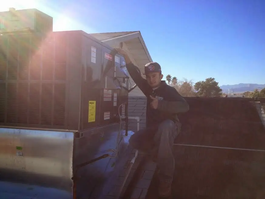 HVAC technician performing Heat Pump Repair on a rooftop unit in Dumont